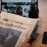Birou de redacție cu ziare, notițe și o ceașcă de cafea, unde se aleg subiectele zilei