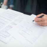 Cetățean care depune o petiție scrisă la ghișeul de registratură al unei instituții publice
