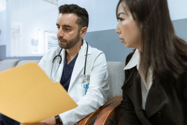 Pacient care discută cu medicul în cabinet, cu o listă de întrebări notate pe hârtie