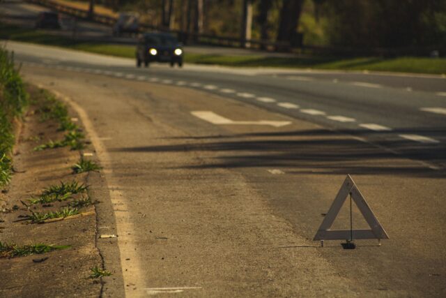 Mașini oprite pe marginea drumului după un accident minor, cu triunghi reflectorizant așezat în spate