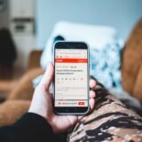 Persoană care citește atent o știre pe telefon înainte de a o distribui mai departe